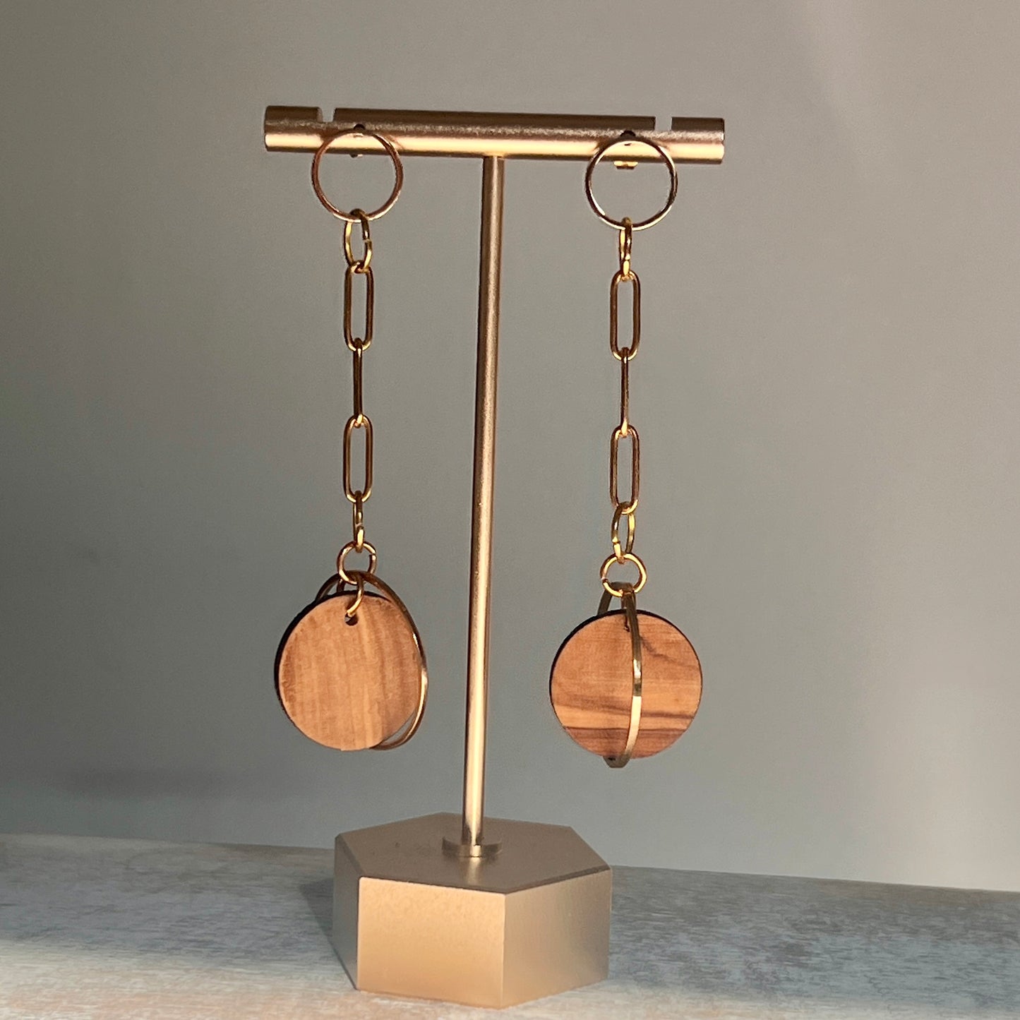 chain link earrings, 3 inches long with olive wood circle at the end hanging on a tbar display
