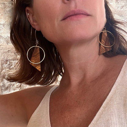 Handcrafted Olive wood and gold hoop earrings - Chloe Earring by Madera Design Studio on model in front of stone wall.