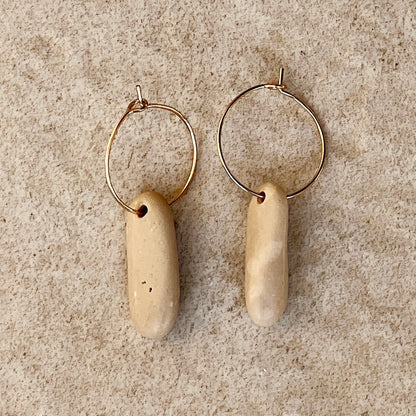 oval pebble stone earring on stone background 