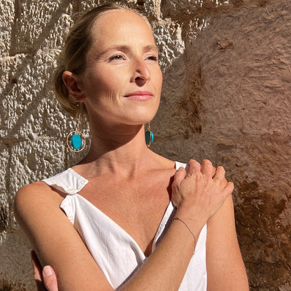 Hand painted aqua threader earrings in gold - on a model by a stone wall in croatia, made by Madera Design Studio 