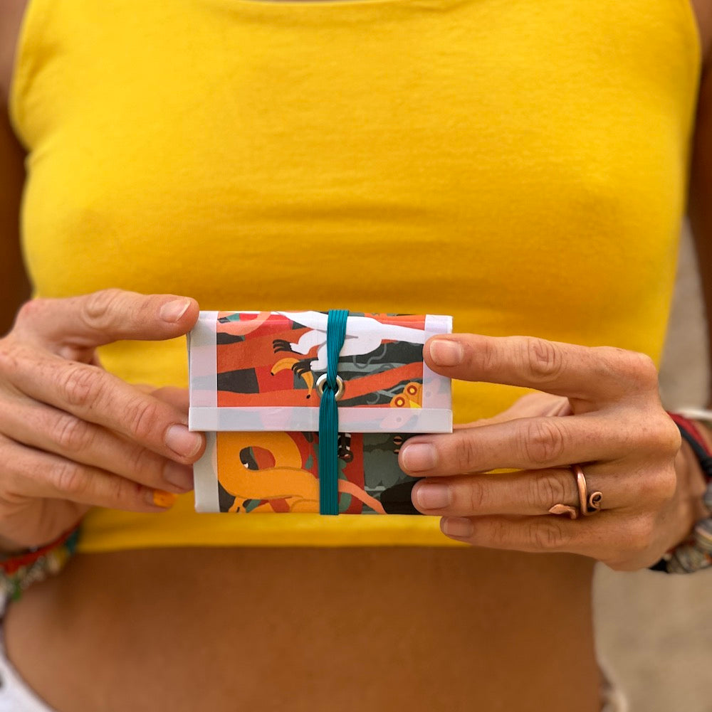 Upcycled carton wallet. orange pattern, held by model