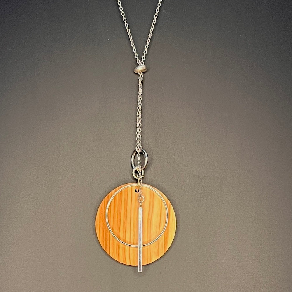 sterling silver lariat with an olive wood disk hanging on black background-madera design studio